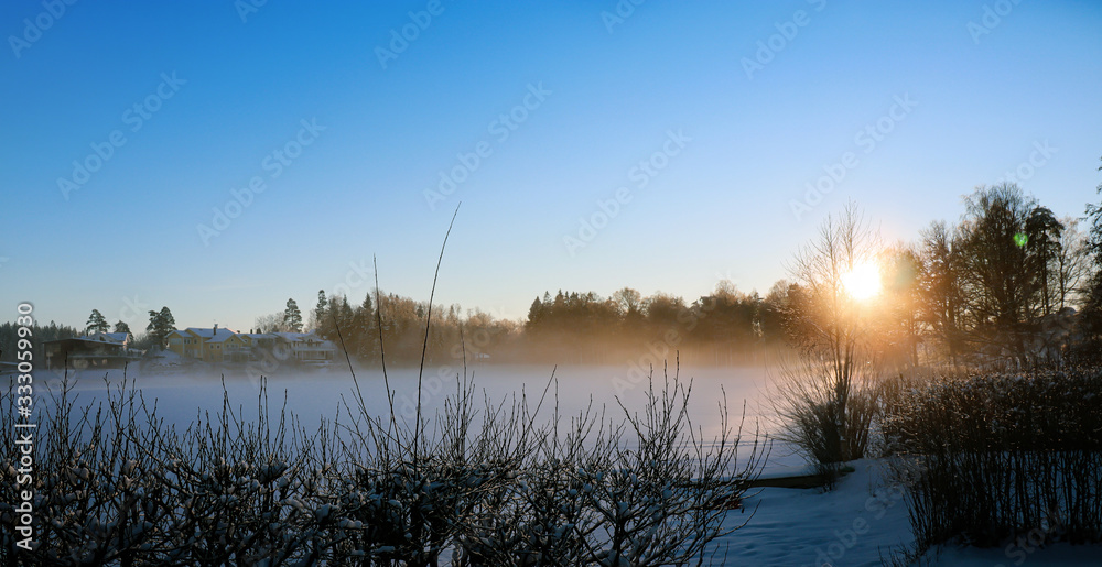 Magic landscape by the lake in the snow. Sunset during yellow hour in Sweden.