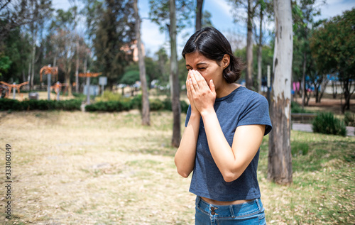 mujer joven estornudando en parque