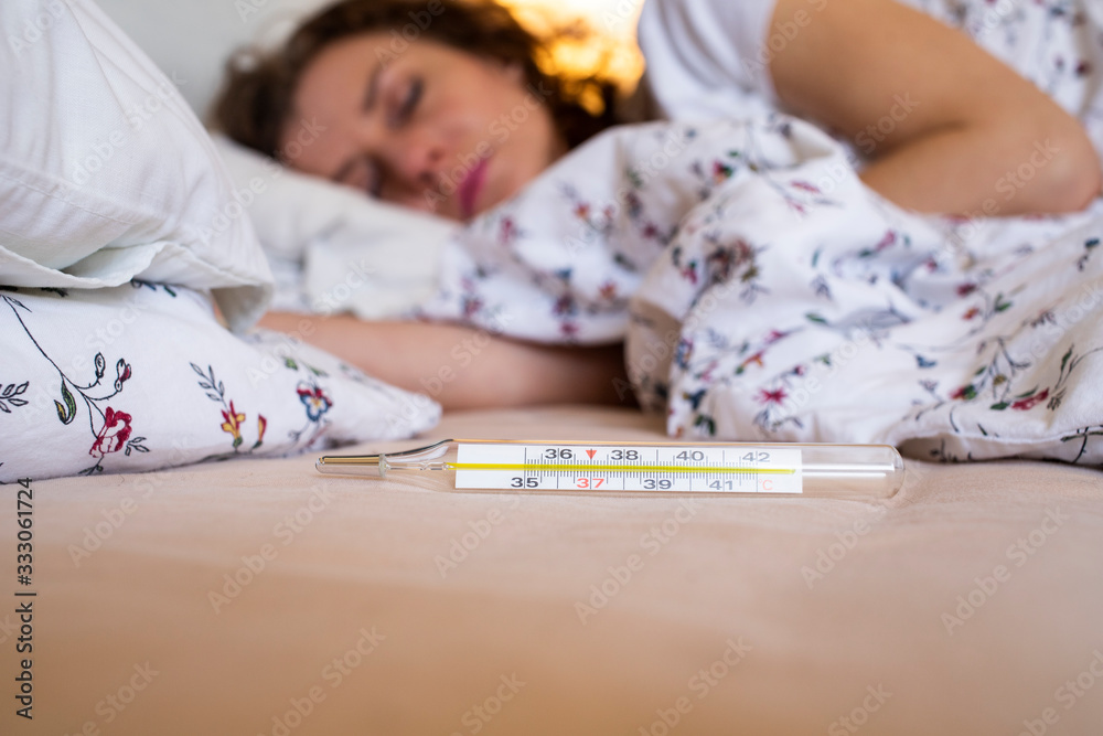 woman in bed with fever focus on thermometer coronavirus or COVID-19 sympthoms woman in bed with fever focus on thermometer coronavirus or COVID-19 sympthoms