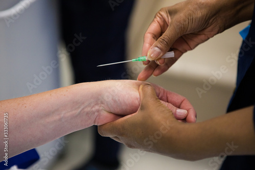 Close up image of a doctor inserting an intravenous line  IV  into the arm of a sick patient