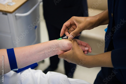Close up image of a doctor inserting an intravenous line, IV, into the arm of a sick patient
