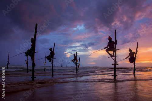 Silhouettes Of The Traditional Sri Lankan Stilt Fishermen At The Sunset In Koggala, Sri Lanka. Stilt Fishing Is A Method Of Fishing Unique To The Island Country Of Sri Lanka (With The Computer Color E