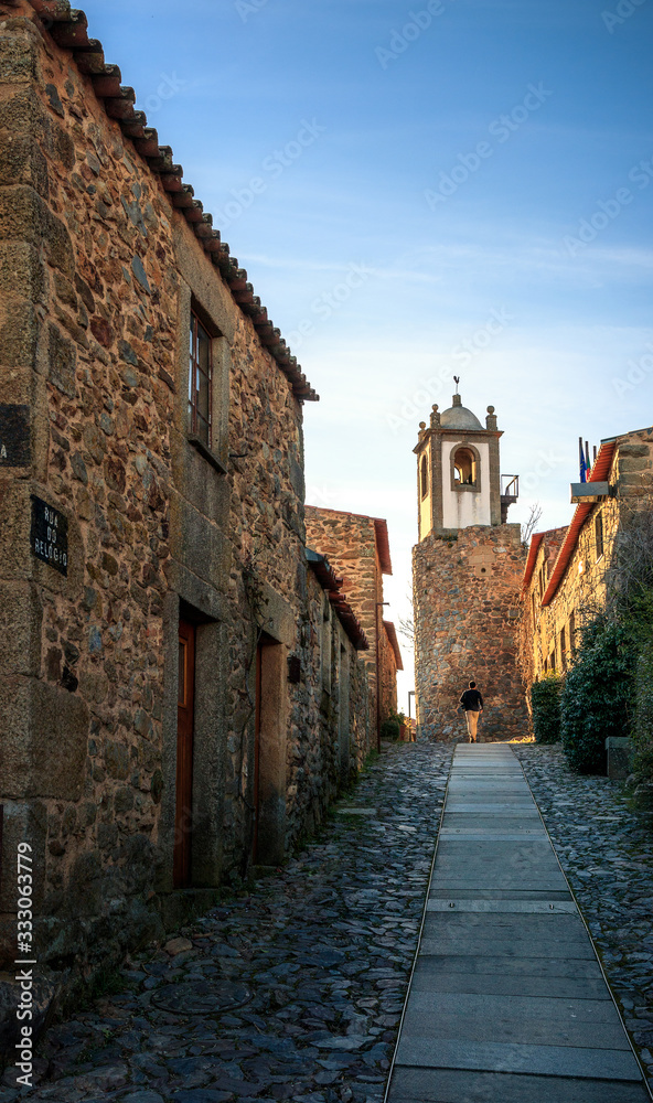 Clock street in the historic village of Castelo Rodrigo, Portugal, with the sunset light illuminating the clock tower at the end of the street.