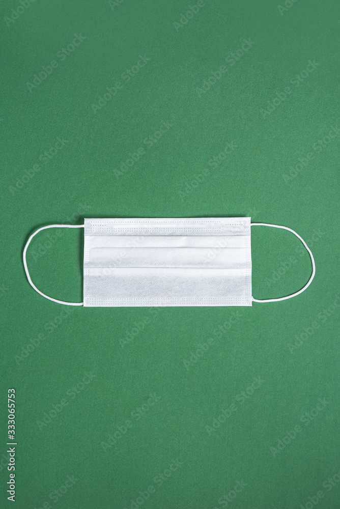 Surgical mask over minimalist green background Surgical mask over minimalist green background
