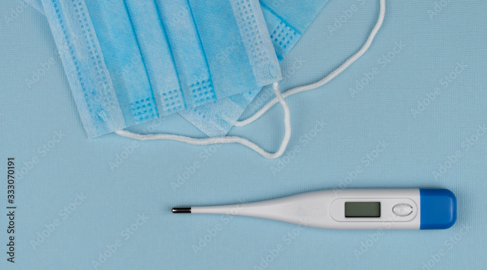Coronavirus prevention surgical masks. electronic thermometer for measuring body temperature. top view.