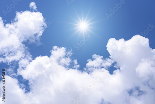 Sun on blue sky with white clouds.