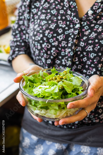 Woman holds green herbal leaves fresh detox salad in glass bowl in hands. Vegan, vegetarian healthy diet food