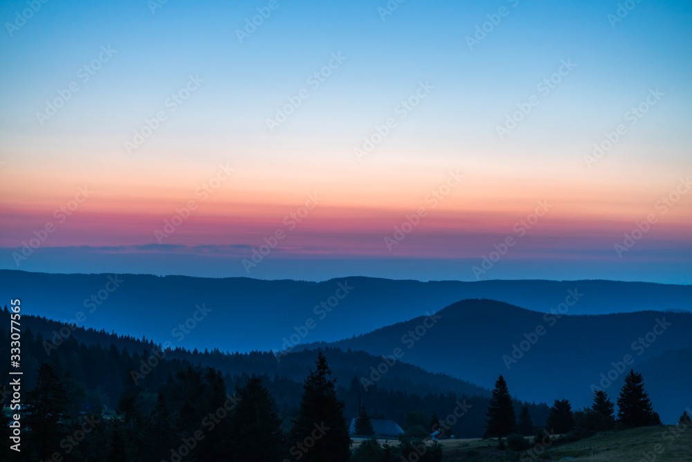 Naklejka premium Sunrise over mountains, blue sky, and orange cloulds on the horizon; natrual landscape in the morning