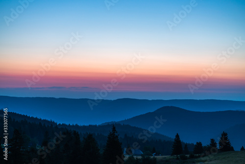 Sunrise over mountains, blue sky, and orange cloulds on the horizon; natrual landscape in the morning photo