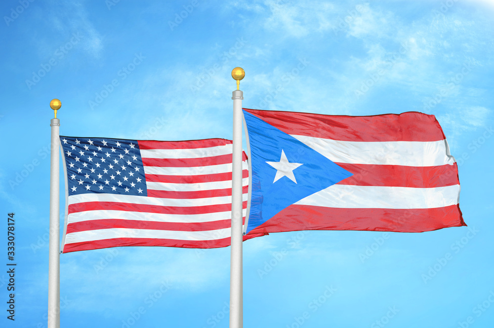 United States and Puerto Rico two flags on flagpoles and blue cloudy sky United States and Puerto Rico two flags on flagpoles and blue cloudy sky
