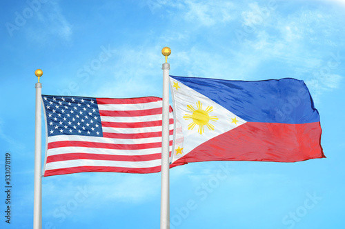 United States and Philippines two flags on flagpoles and blue cloudy sky