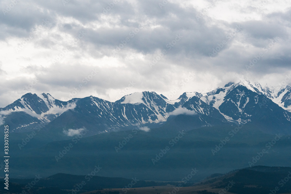 snowy mountain peaks on horizon of valley under clouds, travel to mountain area