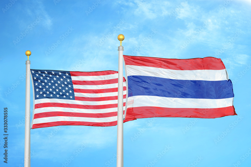Obraz premium United States and Thailand two flags on flagpoles and blue cloudy sky