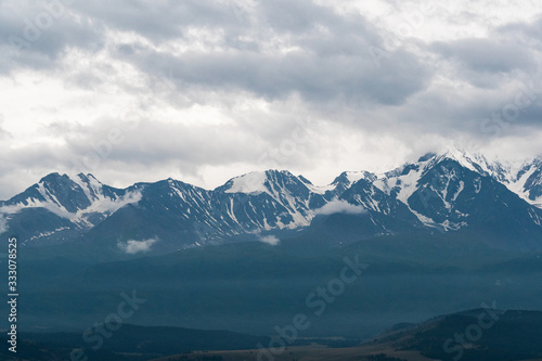 snowy mountain peaks on horizon of valley under clouds, travel to mountain area © Koirill