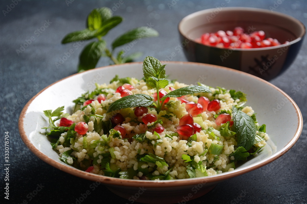 Healthy salad with couscous, fresh mint, cucumber, pomegranate, lemon and olive oil. Eastern cuisine. Vegan food concept. Traditional Israeli food Healthy salad with couscous, fresh mint, cucumber, pomegranate, lemon and olive oil. Eastern cuisine. Vegan food concept. Traditional Israeli food