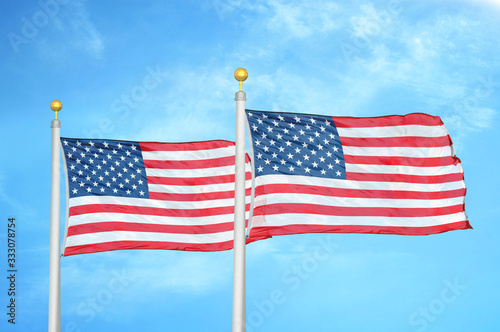 United States and United States two flags on flagpoles and blue cloudy sky