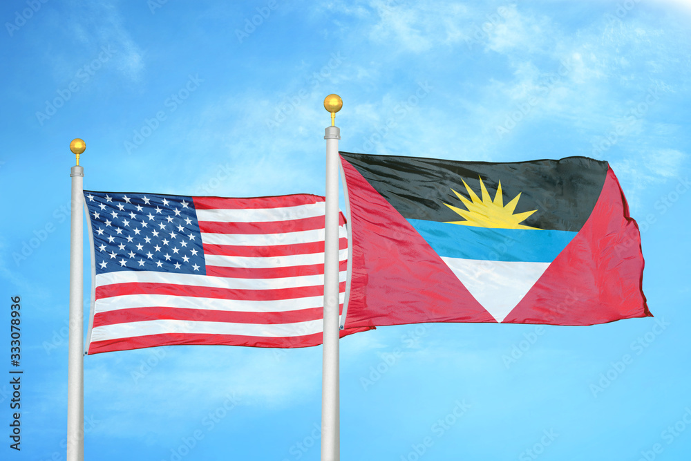 United States and Antigua and Barbuda two flags on flagpoles and blue cloudy sky United States and Antigua and Barbuda two flags on flagpoles and blue cloudy sky