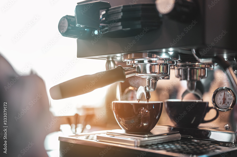 Close-up coffee maker that is professionally extracting coffee by barista with a deep white glass in the evening sun light. coffee, extraction, deep, machine, make, barista concept.