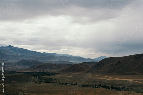 mountain valley under cloudy sky, rock ridge on horizon, hiking in mountains, rest and meditation in nature