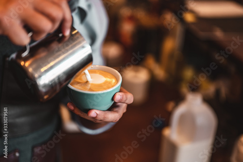 Close-up of professionally extracting coffee by barista with a pouring steamed milk into coffee cup making beautiful latte art. coffee  extraction  deep  cup  art  barista concept.