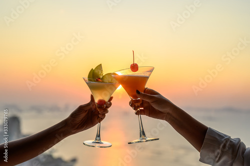 Couple enjoying of Cheers glass of cocktail in a restaurant  at sunset view sea. Cocktail, Couple, Honeymoon, Dinner, Wine, Romantic concept. photo