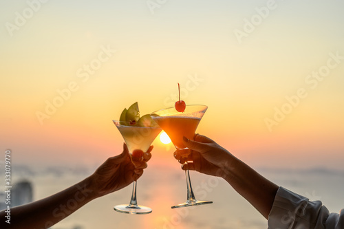 Couple enjoying of Cheers glass of cocktail in a restaurant at sunset view sea. Cocktail, Couple, Honeymoon, Dinner, Wine, Romantic concept.