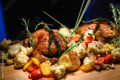 Close-up of a large turkey decorated with various vegetables around and served to a happy family on a flat wooden table. Chicken, turkey, vegetable, large, food, party, lifestyle concept.