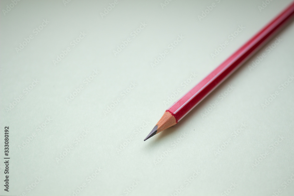 One red pencil on a light green background. One red pencil on a light green background.