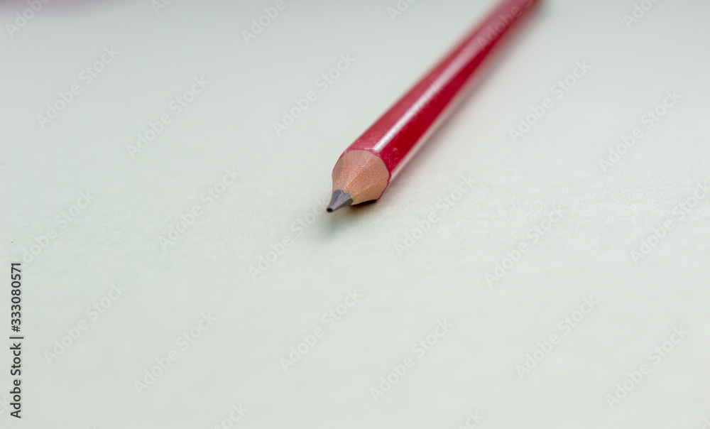One red pencil on a light green background. One red pencil on a light green background.