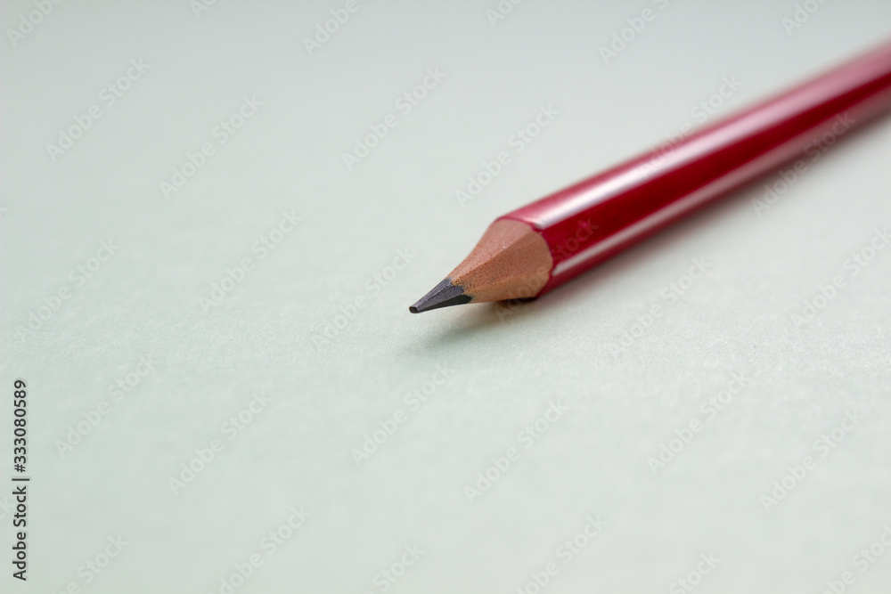 One red pencil on a light green background. One red pencil on a light green background.