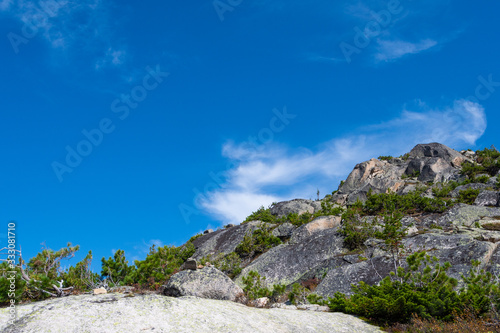 rocky ridge under blue sky in mountain valley, journey of climbers on sheer cliffs