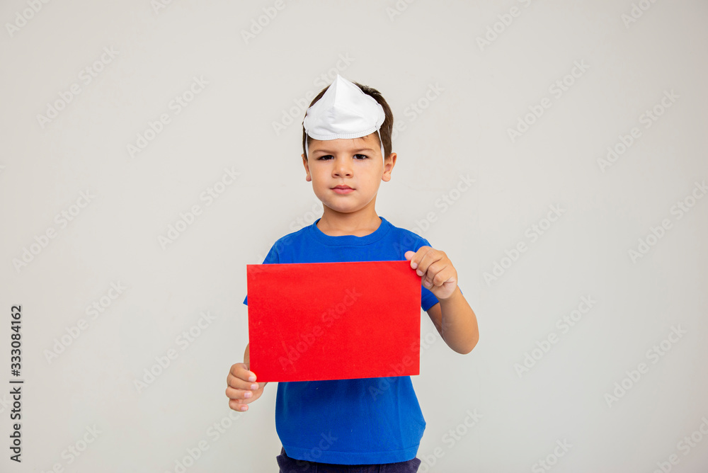 Caucasian boy with surgical mask on his head holding blank sheet. Caucasian boy with surgical mask on his head holding blank sheet.