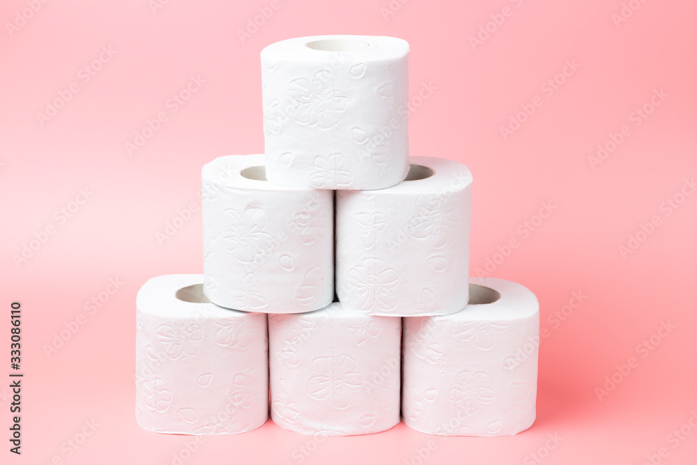 A stack of white rolls in toilet paper on a pink background close up. A stack of white rolls in toilet paper on a pink background close up.