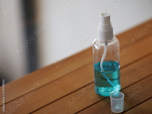 Alcoholic 70 percent in clear bottle on the wooden desk for spray washing clean dirty kill to prevent germs protect colona virus, covid 19 photo