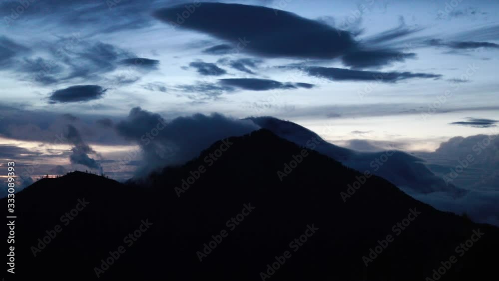 Scenic sunset view of Mount Batur, Bali with dramatic clouds and light in the sky. Beautiful Asian island paradise landscape and colorful light of setting sun on the horizon. Scenic sunset view of Mount Batur, Bali with dramatic clouds and light in the sky. Beautiful Asian island paradise landscape and colorful light of setting sun on the horizon.