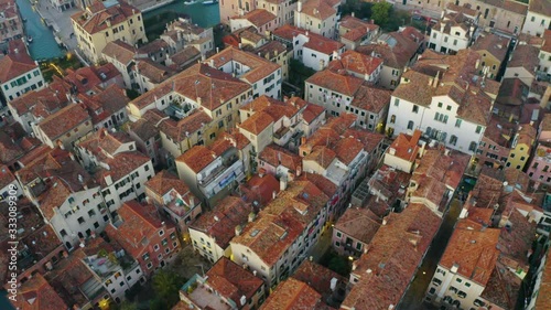 Aerial, tracking, drone shot over colorful buildings, in Venice city, at sunset, in Northern Italy photo