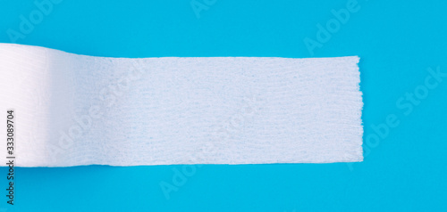 Toilet paper roll on the bright blue background. Coronavirus COVID-19 pandemic panic shopping, social distancing concept. Bright monochrome drop in wide screen banner format with place for text
