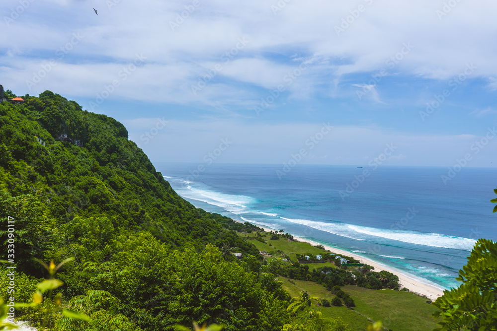 The beautiful nature of Indonesia and the island of Bali. Slopes and cliffs overlooking the waves of the blue ocean. Tropical and exotic view of travel to Asia