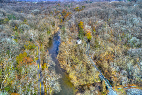 Aerial View of Woods in Fall Colors with a Road, Stream and House photo