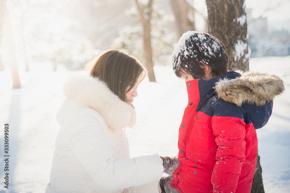 Asian mother and son enjoying snowy winter day outdoors Asian mother and son enjoying snowy winter day outdoors