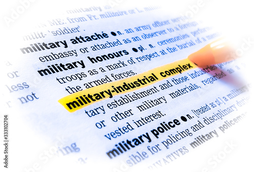 A close up of the word: MILITARY-INDUSTRIAL COMPLEX in a dictionary, highlighted in yellow and showing part of its definition. photo