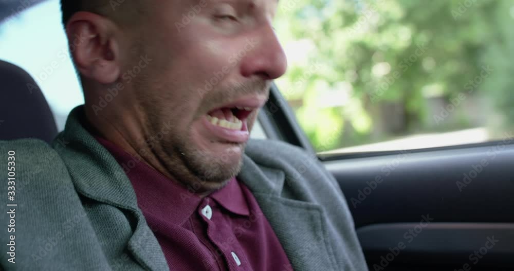 Portrait of man in car gets mad from the fever and sneezes strongly