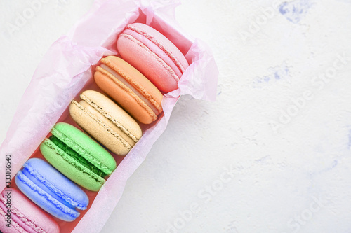 Box with different tasty macarons on white background photo