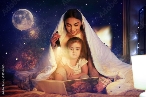 Mother and her little daughter reading bedtime story at home