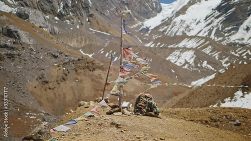 Pole with ragged prayer flags stand on mountain edge, landmark at snow highlands