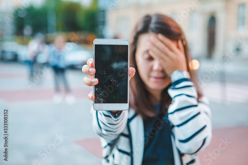 sad woman showing cracked mobile screen after drop photo