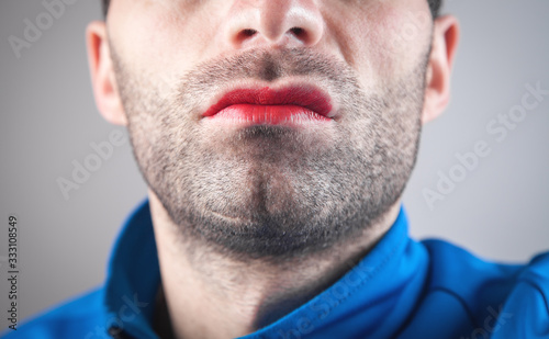Caucasian man with red lipstick on his lips.