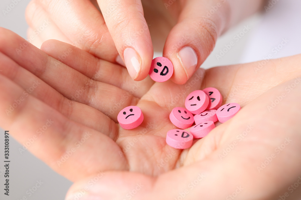 Woman holding pills with drawn faces, closeup Woman holding pills with drawn faces, closeup