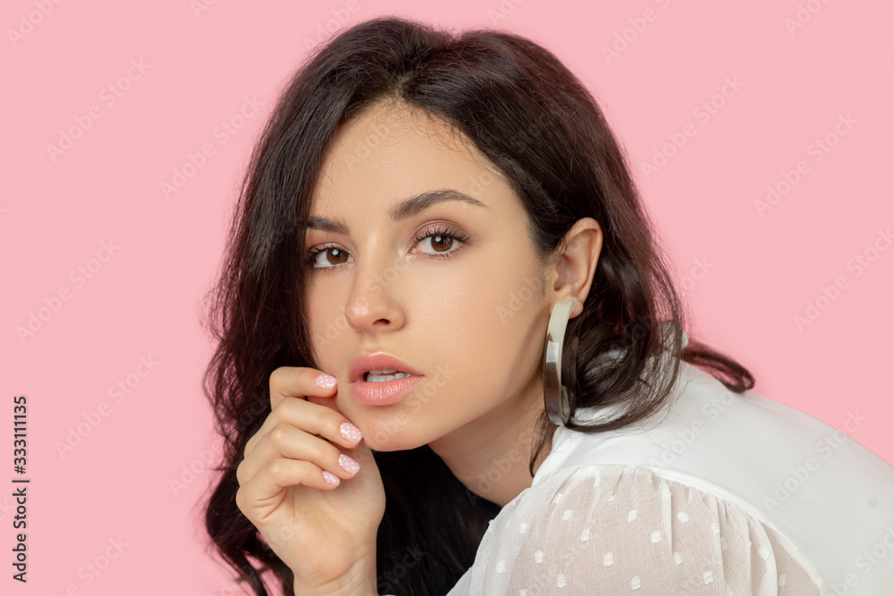 Fototapeta premium Young pretty brunette woman in a white blouse looking thoughtful