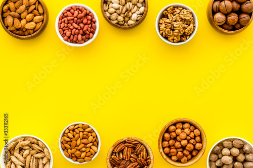 Set of macadamia, hazelnut, walnut, almond, pistachio, pecans nuts on yellow background top-down frame copy space